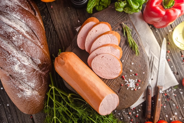Photo rustic wooden background, top and side shot, a large home-made sausage lies on a cutting board, cut