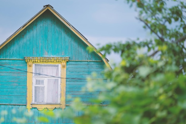 rustiek landhuis met een driehoekig dak en raam met geel frame tegen de lucht