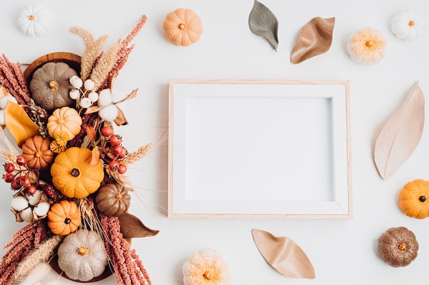 Rustiek model met leeg frame en herfsttafeldecoratie. Bloemen interieur voor herfstvakanties met handgemaakte pompoenen. Vakantie wenskaart. Flatlay, bovenaanzicht