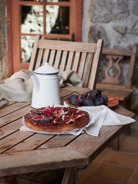 Rustieke houten tafel klaar om theetijd te delen met vijgentaart en witte theepot op het terras of in de tuin