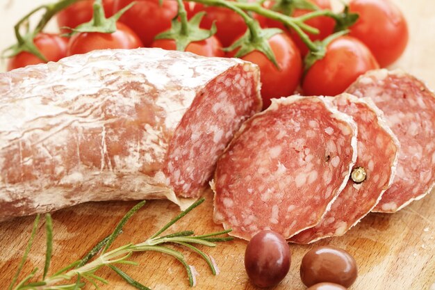 Rustieke Italiaanse snackclose-up - salami, tomaten, kruiden en olijven