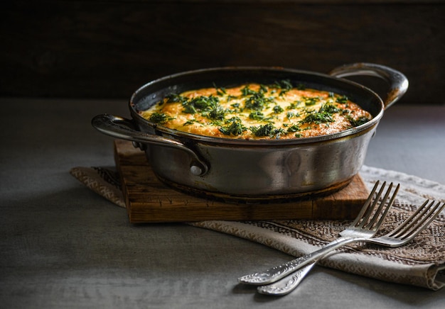 Rustieke omelet met aardappelen en kruiden in een metalen pan op de keukentafel