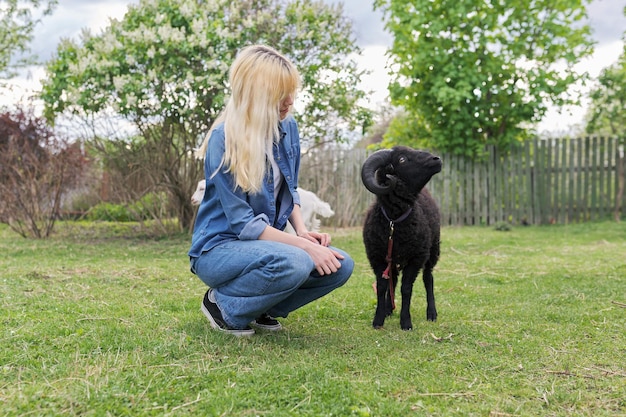 Rustieke stijl kleine dierenboerderij jonge vrouw tiener spelen zwarte ram aan te raken