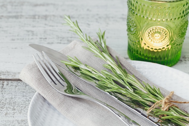 Rustieke tafel setting met rozemarijn op licht houten tafel. vakantiedecoratie in provençaalse stijl. romantisch diner.