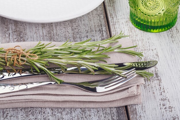 Rustieke tafel setting met rozemarijn op licht houten tafel. Vakantiedecoratie in Provençaalse stijl. Romantisch diner.