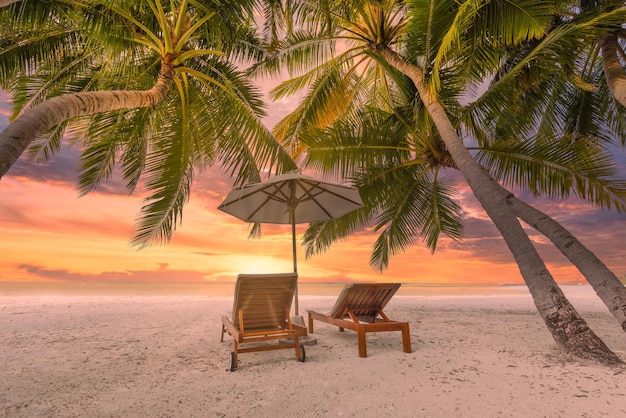 Rustig tropisch zonsonderganglandschap, twee ligbedden, ligstoelen, parasol onder palmboom. Wit zand, zee