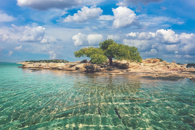 Rustige baai met een klein rotseilandje en zandstrand Lagonisi strand Halkidiki Griekenland