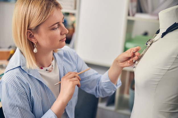 Foto rustige juwelier die een ketting aanraakt terwijl hij een potlood in de hand houdt