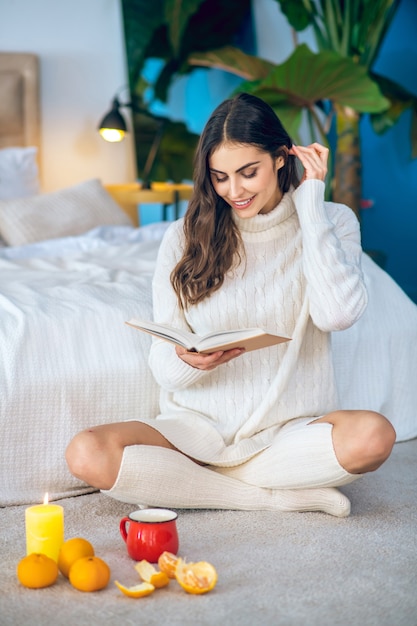 Rustige sfeer. Jonge mooie vrouw die op de vloer situeert en een boek leest