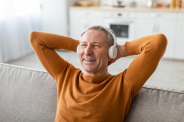 Rustige volwassen man die thuis naar muziek luistert