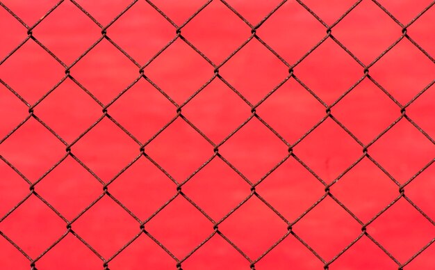 Rusty chain link fence on red blur background, shallow focus