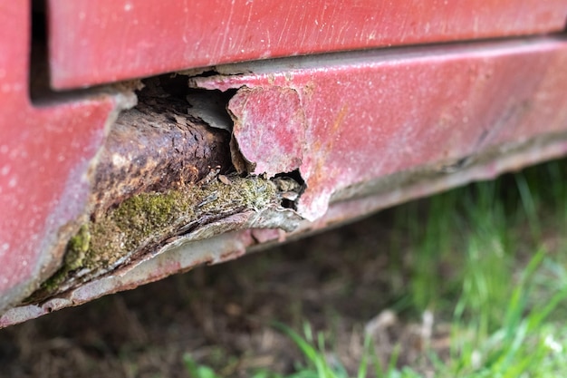 さびた運転免許証の敷居冬後の赤い古い車の車体の腐食保護されていない車体への冬の試薬の影響下部の左側の腐った敷居の損傷