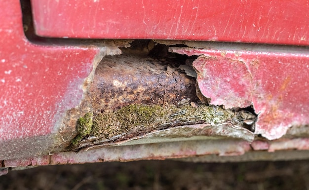 Photo rusty driver's door sills corrosion of the body of a red old car after winter influence of reagents