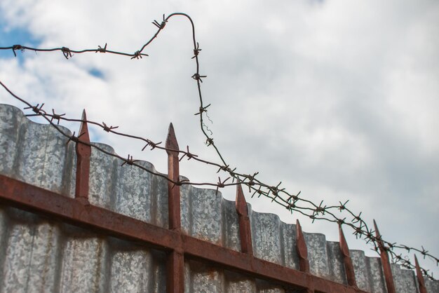 Photo rusty fence with barbed wire razor wire freedom or danger copyspace for text