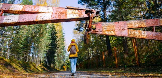 Rusty iron gate, closed road to the park. Woman violated the border of protected area. Focus on padlock.