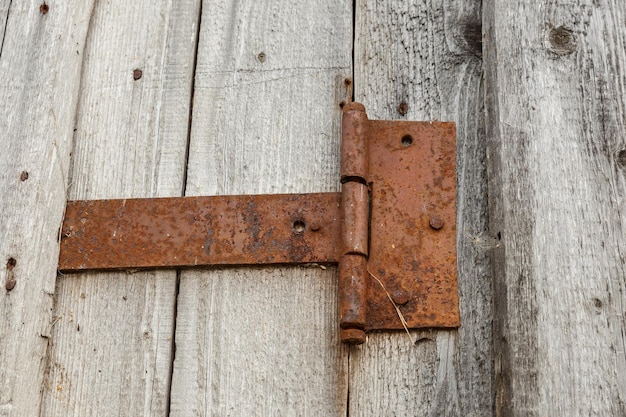 Photo rusty metal door hinge. door hinge on a wooden wall.