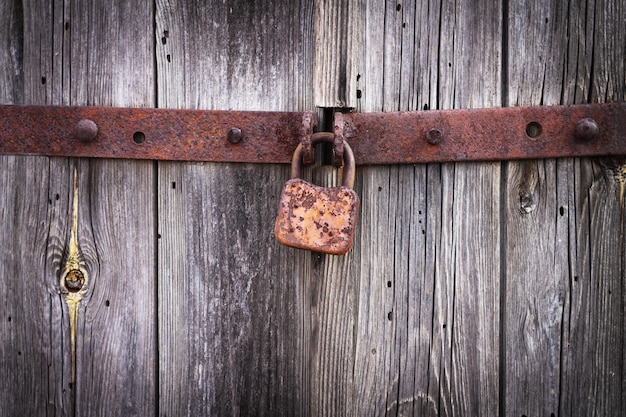 Rusty padlock hanging on old vintage wooden door