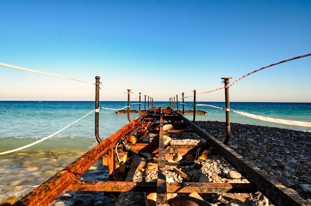 Foto un molo arrugginito sul mare contro un cielo blu limpido