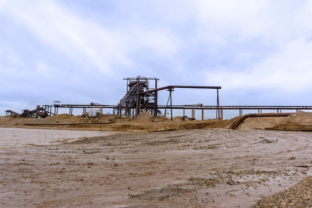 Rusty pipe on the river bank and stationary rusty gravitational sand and gravel separator