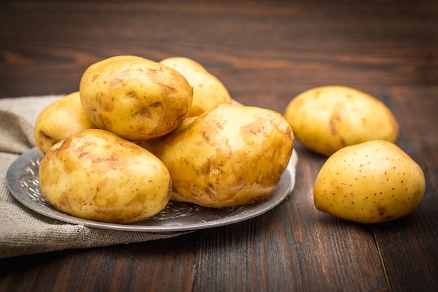 Ruwe aardappels op een bruine houten achtergrond