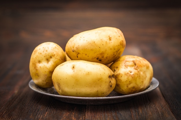 Ruwe aardappels op een bruine houten achtergrond