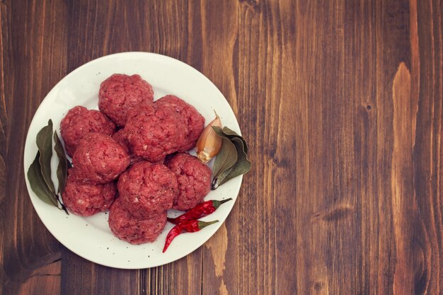 Ruwe gehaktballen op schotel op houten oppervlak