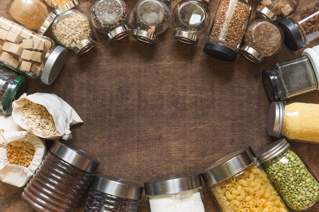 Ruwe granen, granen en pasta in glazen potten op houten tafel achtergrond