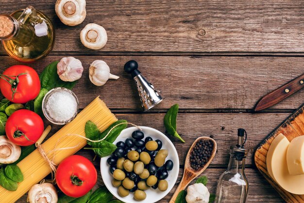 Foto ruwe ingrediënten voor de bereiding van italiaanse pasta spaghetti basilicum tomaten olijven en olijfolie o