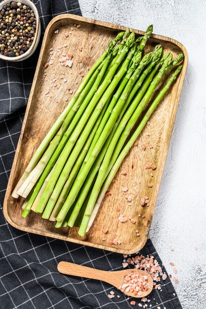 Ruwe jonge groene asperges in een houten kom