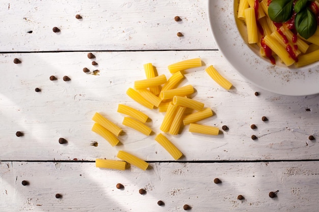 Ruwe macaroni en heel papier op de witte houten tafel Bovenaanzicht