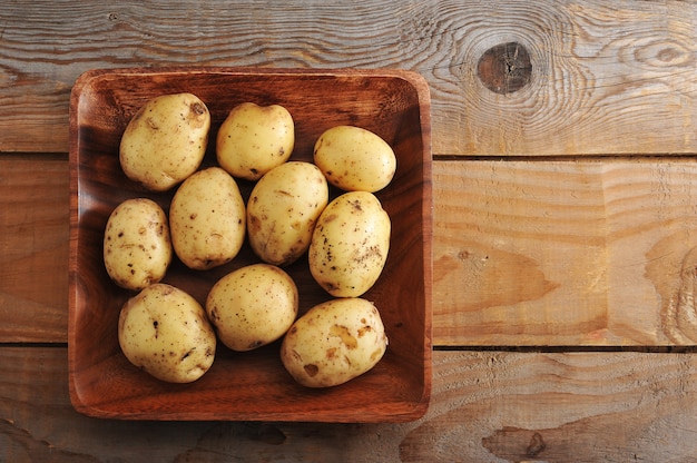 Ruwe nieuwe aardappelen in de schil op rustieke houten oppervlak