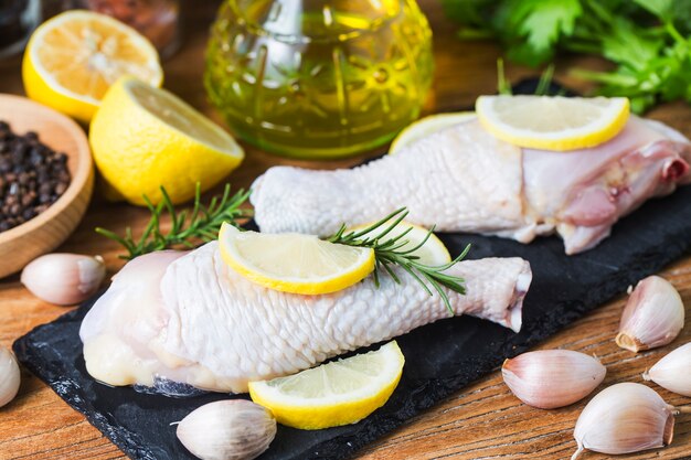 Ruwe ongekookte kippenbenen, trommelstokken op houten raad, vlees met ingrediënten voor het koken