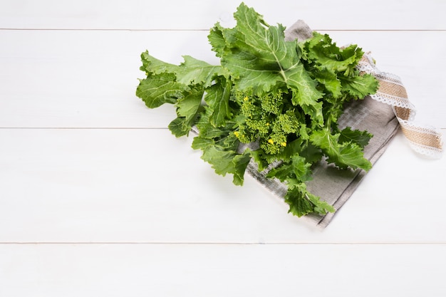 Ruwe organische raapgreens klaar om op een witte houten achtergrond met exemplaarruimte te eten