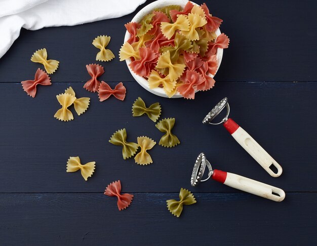 Ruwe pasta in de vorm van strikken in een houten ronde plaat en witte textiel servet