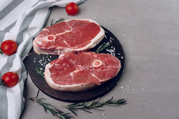 Ruwe rib-eye biefstuk op houten snijplank op grijze achtergrond