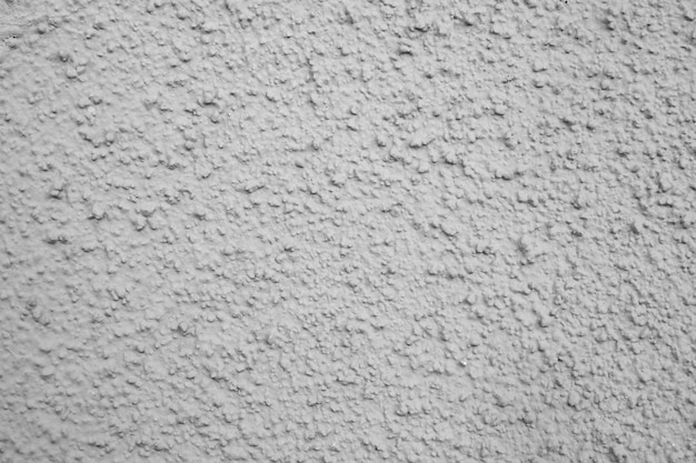 Foto ruwe textuur van de grijze muur, de gevel van het huis met een bolle structuur van gips