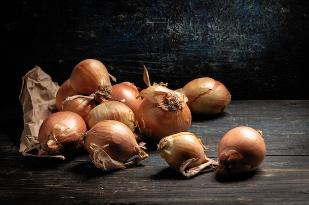 Ruwe uien leggen op een grijze tafel, munt op de achtergrond, zwarte achtergrond