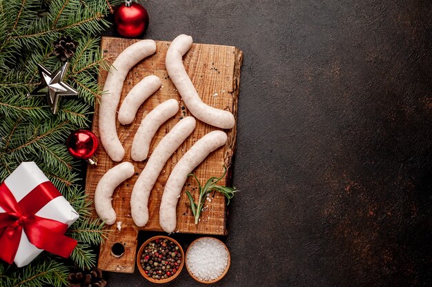 Ruwe worstjes op een houten bord met kerstversiering naast