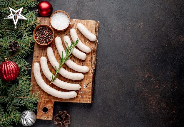 Ruwe worstjes op een houten bord met kerstversiering naast