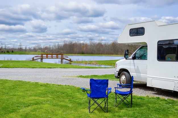 RV (camper) and chairs in camping, family vacation travel, holiday trip in motorhome