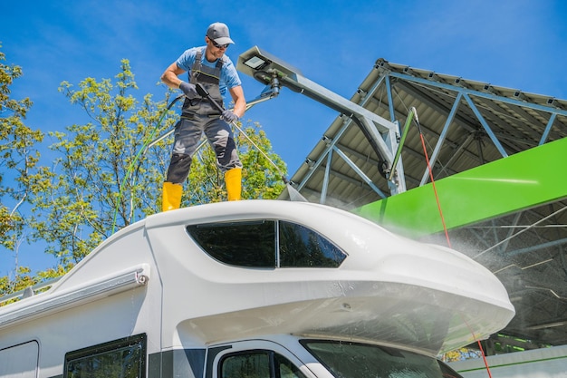 RV Camper Rentals Worker Cleaning Motorhome Using Pressure Washer