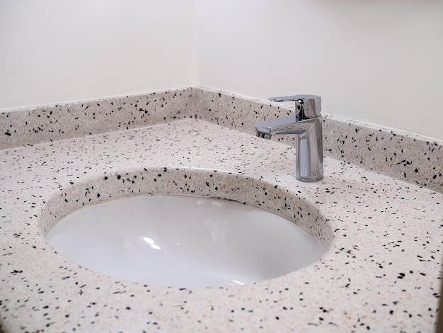 RVS chroom zilveren kraan of kraan in ronde vorm van terrazzo tegels wastafel op witte muur achtergrond Retro stijl badkamer of damestoilet interieur