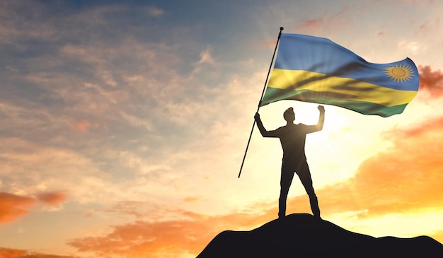 Rwanda flag being waved by a man celebrating success at the top of a mountain 3D Rendering