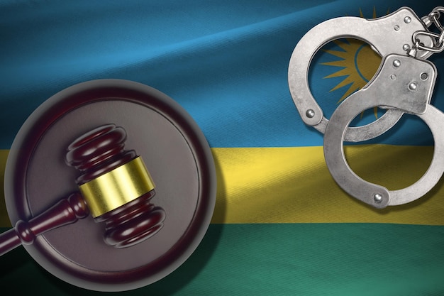 Rwanda-vlag met rechterhamer en handboeien in donkere kamer Concept van criminele en strafachtergrond voor oordeelsonderwerpen