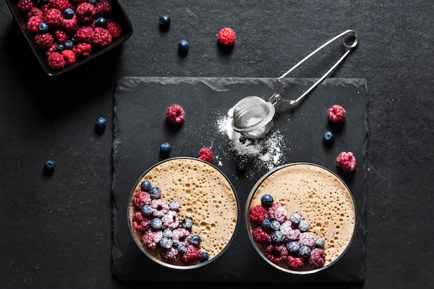 Photo ryazhenka (fermented baked milk) mousse in glass bowls decorated with fresh berries. flat lay, top view.