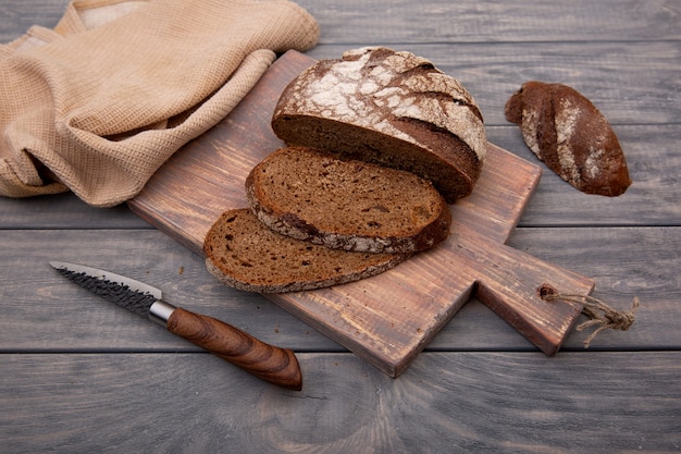 素朴な木で作られたナイフで木の板に細かく切ったライ麦パンの丸いパン。