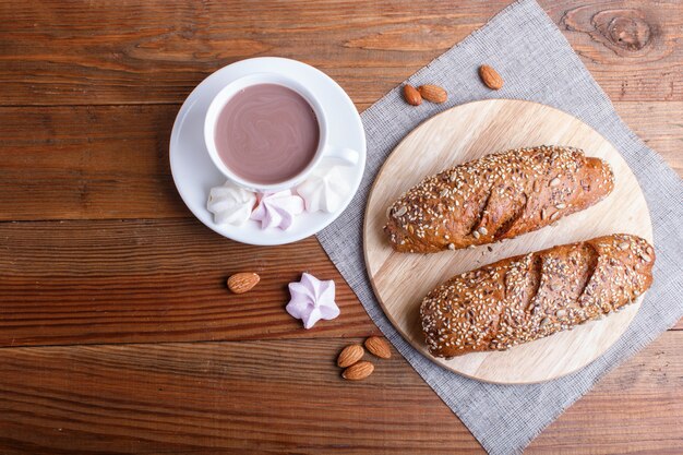 Rye bread with sunflower seeds, sesame and flax with cup of cocoa on brown wooden surface.