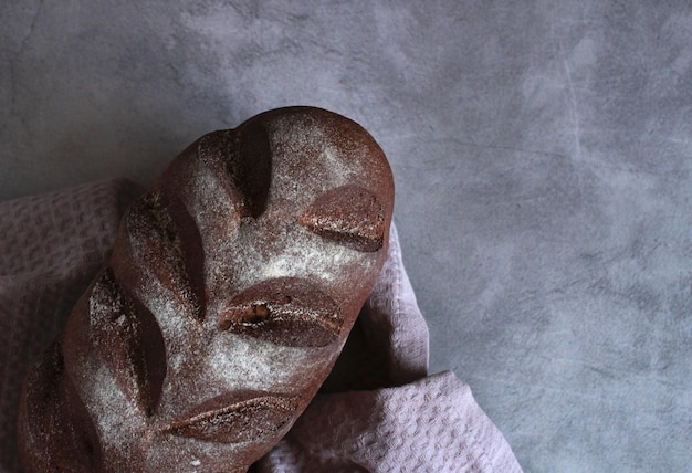 Rye dark beautiful bread with textiles on a gray background under the concrete