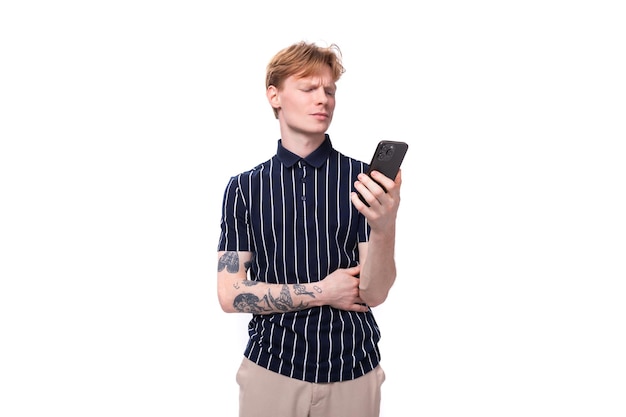 S blond man dressed in a tshirt with tattoos sits on the phone