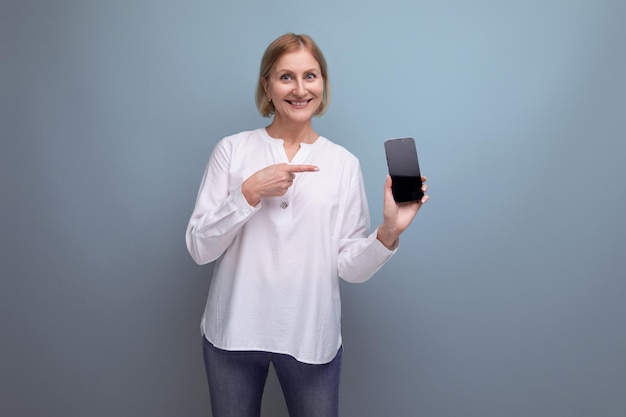 Светловолосая женщина с макетом телефона на фоне студии